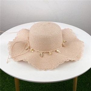 Detailed close-up of wavy brim straw hat with woven hollow patterns and natural shells