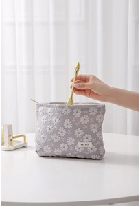 Détail du rangement d'un appareil de beauté doré dans la pochette en toile brodée