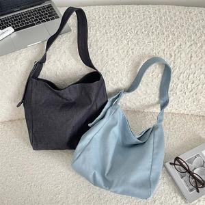 Detail of large tie-dye canvas hobo bags with wide straps next to a laptop