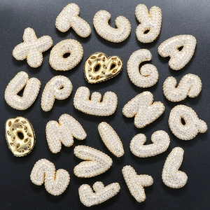 Macro shot of gold-plated copper alphabet pendants with sparkling zircon stones