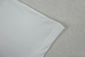 Close-up of white knitted fabric detail showing clean stitching and hemline texture