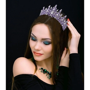 Close-up of a sparkling purple tiara with rhinestones worn by a model in profile