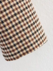 Nahaufnahme der klassischen braunen Karo-Stoffstruktur und Nähte eines Doppelreiher-Blazers