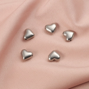 Cinq pendentifs cœur en acier inoxydable poli sur un tissu en soie rose élégant