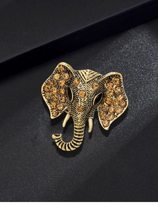 Detailed macro shot of vintage gold elephant brooch with amber rhinestones on black
