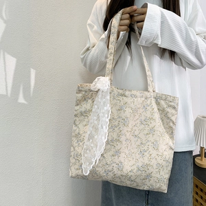 Detailed shot of floral canvas tote bag with a white lace bow charm in a soft light