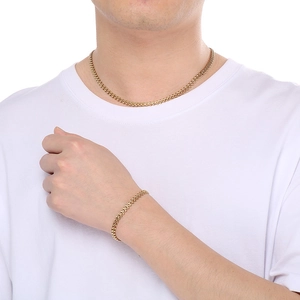 Close-up of gold wheat chain necklace and bracelet set worn by a model on white background