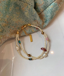 Detail of bohemian double-layer bracelet with freshwater pearls and gold charms