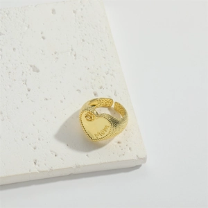 Detail of gold heart ring with Mom engraving and textured band on stone base