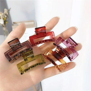 Close-up of four translucent square hair claws in deep red, purple, amber, and olive green