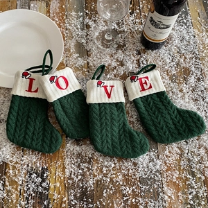 Green knitted Christmas stockings with red LOVE embroidery on rustic snow-covered wood