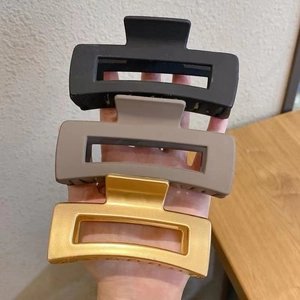 Detail of matte black, taupe, and brushed gold large hair claw clips in a three-piece set