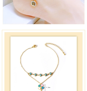 Detail of double-layered gold anklet featuring turquoise beads and clover pendant