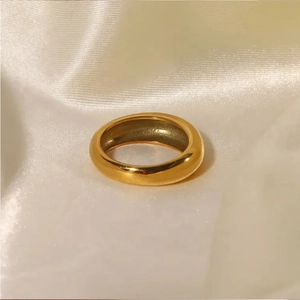 Polierter vergoldeter Edelstahl-Ring auf weißem Seidenstoff im eleganten Design