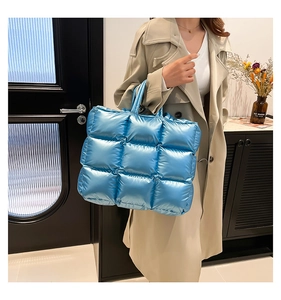 Dettaglio della borsa tote trapuntata blu metallizzata con design imbottito su modella
