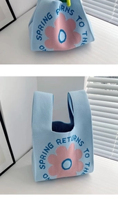 Detail of blue knitted gift bag featuring pink flower design and Spring embroidery