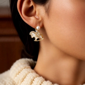 Détail de la boucle d'oreille cheval à bascule dorée 14k et perle sur mannequin