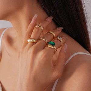 Detailed view of 6-piece vintage gold ring set featuring green gemstones on a female model