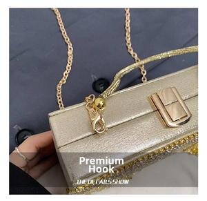 Detail of luxury evening clutch showing gold clasp, rhinestone trim, and chain hook