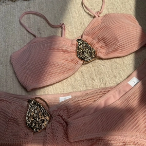 Detail of pink waffle texture bikini with a molten gold metal buckle on white faux fur