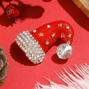 Sparkling Christmas hat brooch with red enamel and crystals on festive pine background