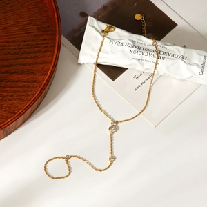 Detail of gold finger bracelet featuring three round white zircons on a wooden tray