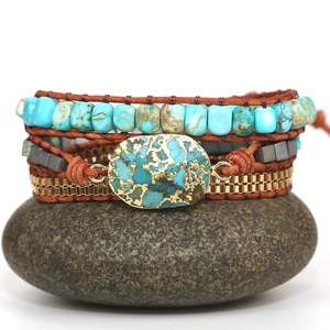 Bohemian multi-layer wrap bracelet featuring turquoise beads and gold chains on a stone
