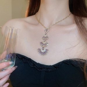 Detail view of a layered fan-shaped pendant necklace with purple crystals on a model
