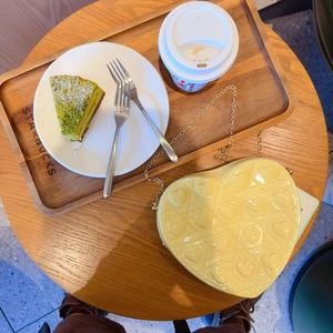 Detail of yellow heart-shaped quilted shoulder bag with gold chain on a cafe table