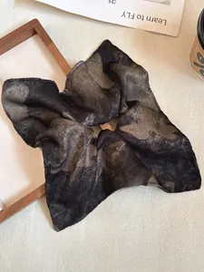 Detailed texture of black and gold marble pattern silk scrunchie on wooden frame