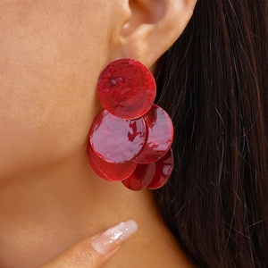Close-up of stylish red tiered round drop earrings with shell-like luster on a model