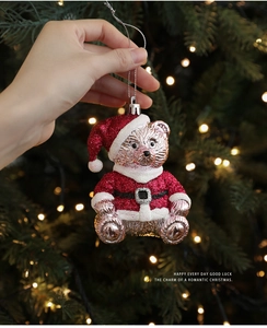 Detail of red glitter Christmas bear ornament held by hand with festive bokeh lights