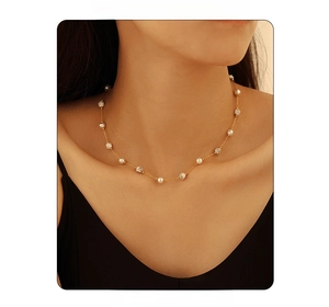 Détail d'un collier doré avec perles blanches et pierre de marbre sur le mannequin
