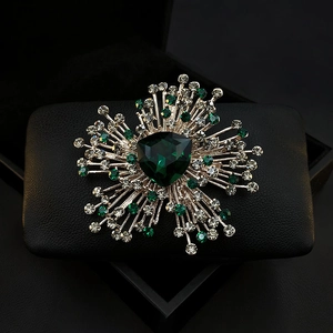 Close-up of a luxury emerald crystal brooch with sparkling rhinestones in a black jewelry box