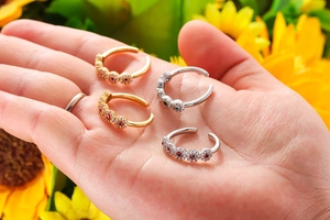 Detail of adjustable evil eye rings set with colorful zircons on a sunflower background