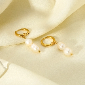 Close-up of double baroque pearls hanging from a 14K gold plated stainless steel earring
