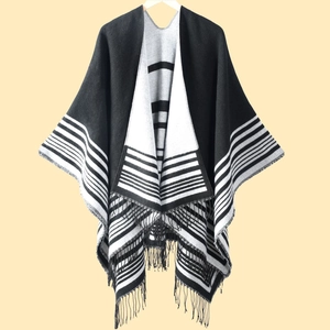 Detail of black and white striped knit poncho featuring elegant long fringe tassel edges