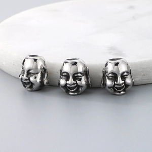 Three silver stainless steel Buddha head spacer beads on white marble background