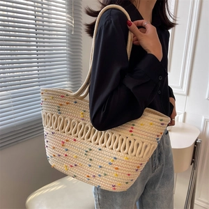 Summer woven tote bag with colorful pom poms on a cream straw shoulder bag for beach trips