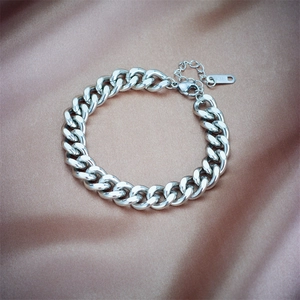 Polished silver cuban link bracelet on champagne satin background with K18 tag