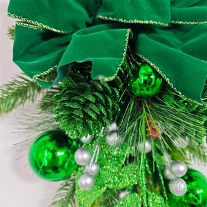 Gros plan du nœud de Noël en velours vert avec bords dorés et décorations de sapin