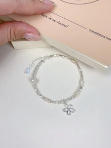 Close-up of S925 silver bracelet with flower pendant and fresh water pearls on a desk