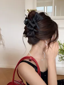Detail of black satin bow hair claws used in an elegant updo hairstyle for women