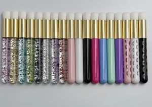 Lash cleansing brushes with various handles, gold ferrules, and soft white bristles detail