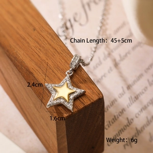 Macro view of gold and silver star pendant necklace with cubic zirconia and size details