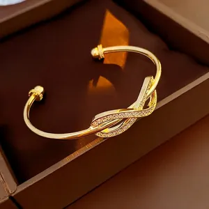 Gold-plated open bangle featuring a sparkling zircon-studded knot on a jewelry box