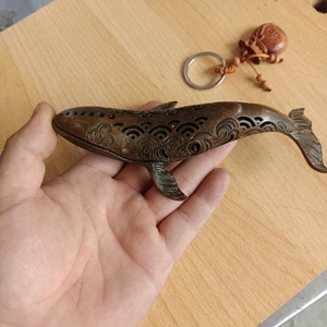 Detailed macro shot of vintage bronze whale incense burner with intricate hollow wave patterns