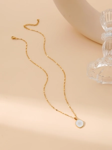 Detail of gold sunburst pendant with white enamel on a delicate sequin link chain