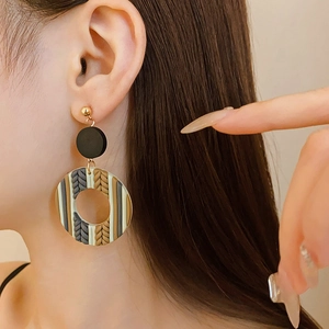 Detail of bohemian geometric round drop earrings with knit texture on a model