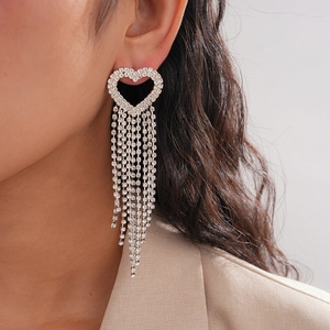 Close-up of heart-shaped silver earrings with long dangling zircon tassels on model